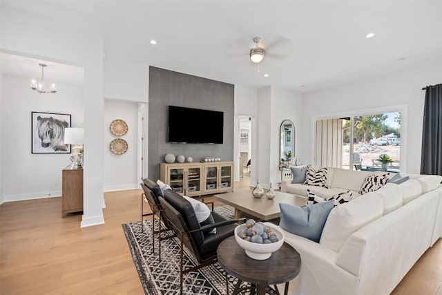 living room with light hardwood / wood-style flooring and ceiling fan with notable chandelier