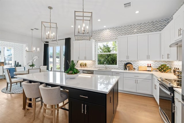 kitchen with electric stove, white cabinetry, a center island, and decorative light fixtures