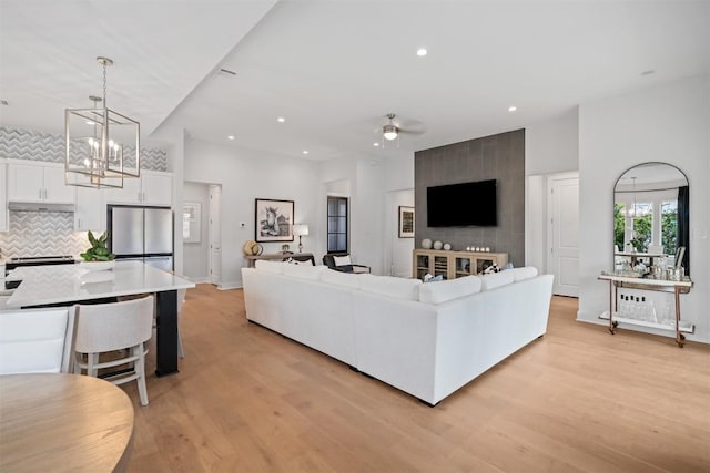 living room with light hardwood / wood-style flooring and ceiling fan with notable chandelier