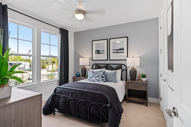 bedroom featuring ceiling fan, light colored carpet, and multiple windows