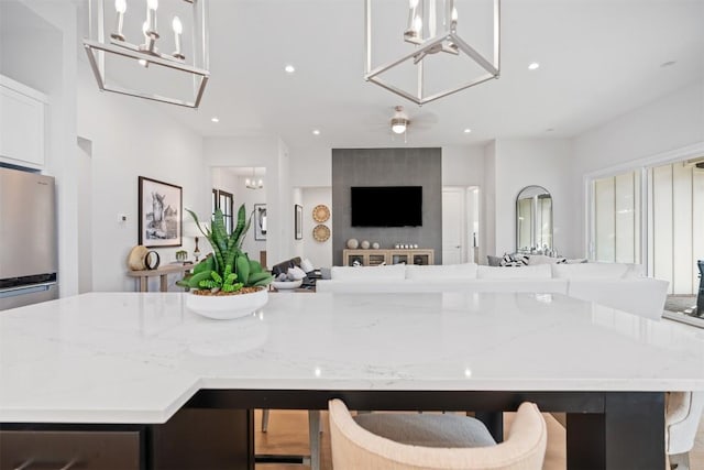 kitchen featuring light stone countertops, ceiling fan, decorative light fixtures, a center island, and a breakfast bar area