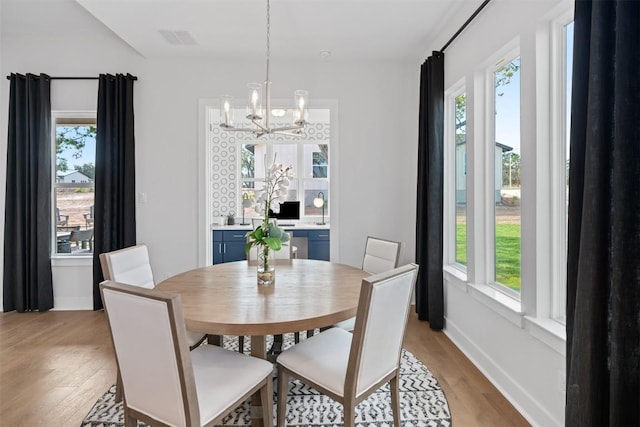 dining space with light hardwood / wood-style floors and a notable chandelier