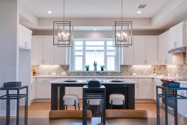 kitchen with a kitchen breakfast bar, light hardwood / wood-style flooring, white cabinetry, and a kitchen island