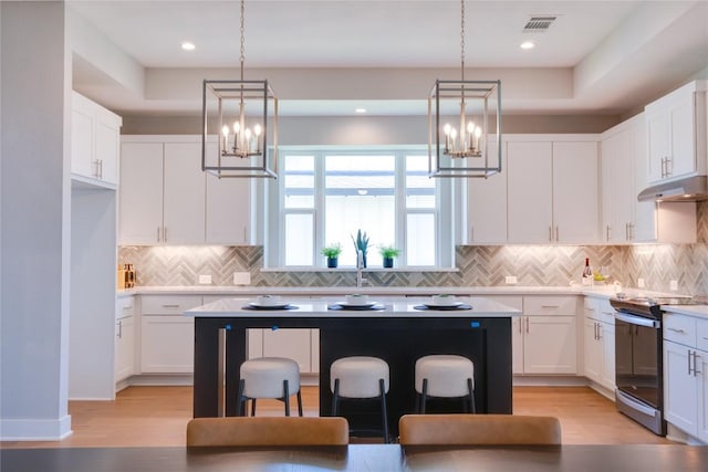 kitchen with white cabinetry, electric range, a center island, and a kitchen breakfast bar