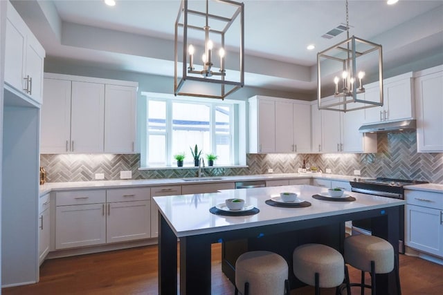 kitchen with decorative light fixtures, white cabinetry, a kitchen island, and sink