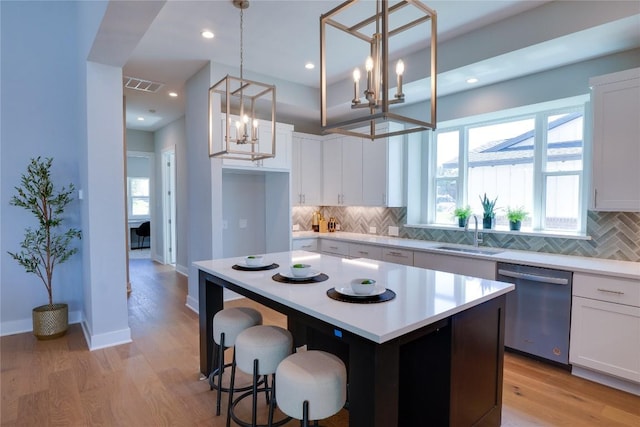 kitchen featuring white cabinets, stainless steel dishwasher, and decorative light fixtures