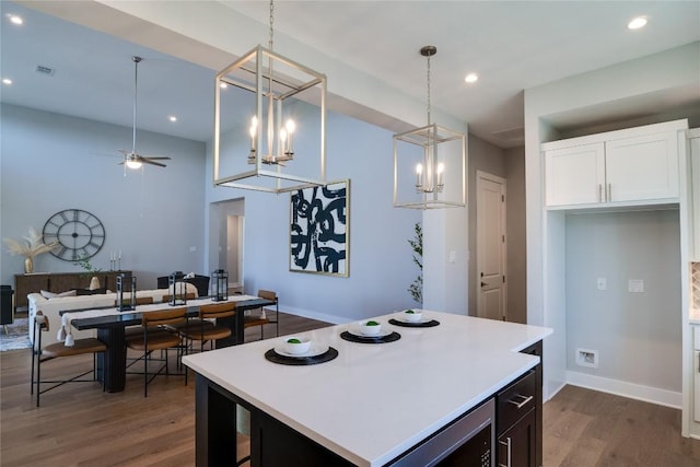 kitchen featuring pendant lighting, ceiling fan, a center island, and white cabinetry