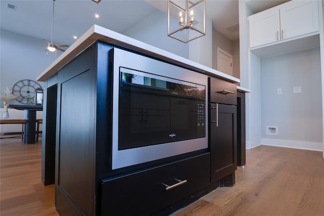 kitchen with white cabinets, pendant lighting, ceiling fan with notable chandelier, and light hardwood / wood-style flooring