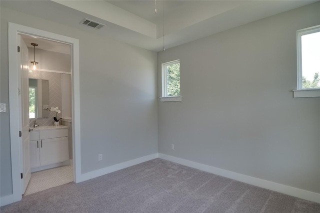 carpeted empty room featuring a raised ceiling