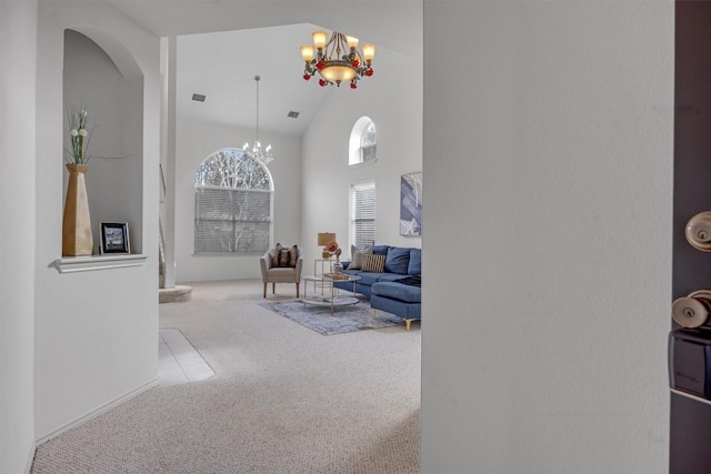 carpeted living room with a high ceiling and an inviting chandelier