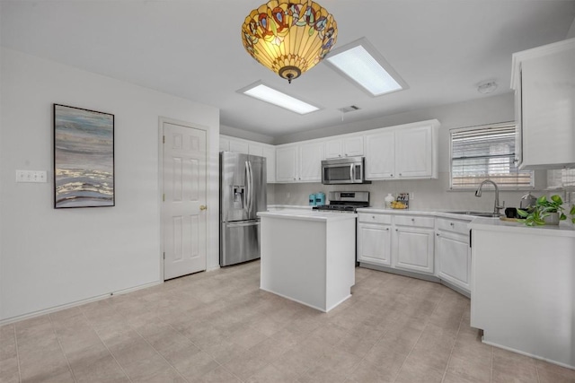 kitchen with pendant lighting, sink, appliances with stainless steel finishes, a kitchen island, and white cabinetry