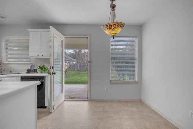 interior space featuring white cabinetry, sink, black dishwasher, decorative light fixtures, and decorative backsplash