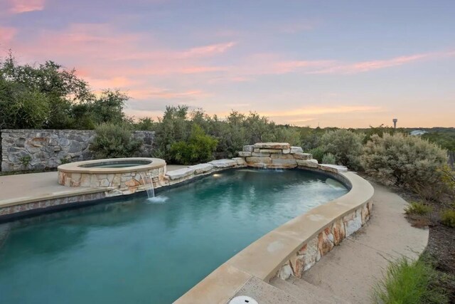 pool at dusk with an in ground hot tub and pool water feature