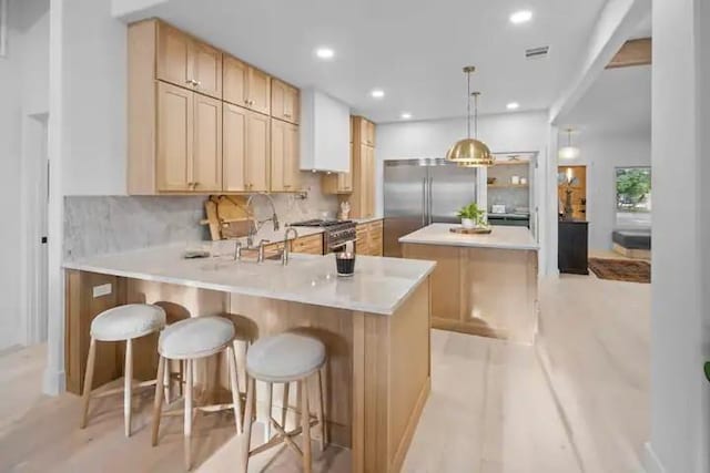 kitchen with a kitchen island, tasteful backsplash, a kitchen breakfast bar, high end appliances, and kitchen peninsula