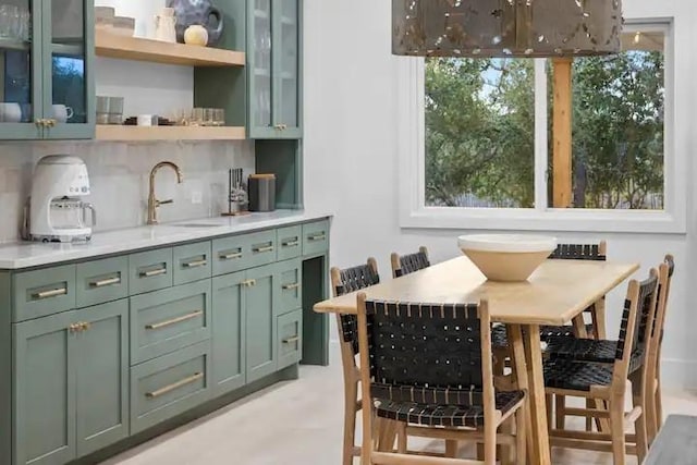 bar with green cabinetry, sink, and backsplash