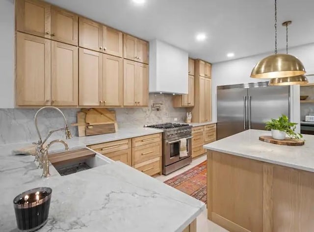 kitchen featuring premium appliances, light stone countertops, sink, and light brown cabinets