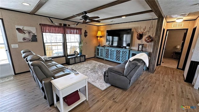 living room featuring ceiling fan, wood-type flooring, and beamed ceiling