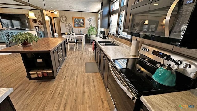 kitchen with sink, stainless steel range with electric cooktop, hanging light fixtures, a center island, and light wood-type flooring