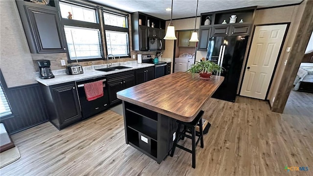 kitchen featuring a kitchen island, sink, hanging light fixtures, black appliances, and light hardwood / wood-style flooring