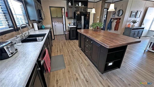 kitchen featuring sink, a center island, black refrigerator with ice dispenser, pendant lighting, and washer and clothes dryer