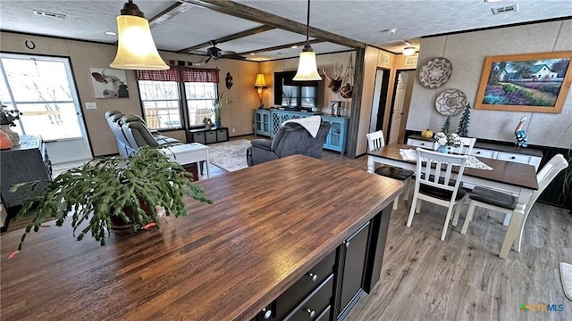 dining area featuring beamed ceiling, ceiling fan, light hardwood / wood-style floors, and a textured ceiling