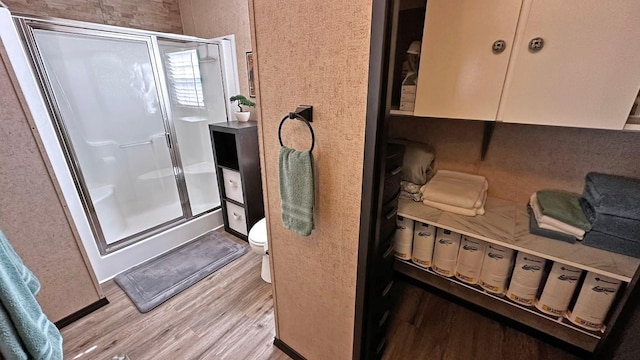 bathroom with hardwood / wood-style flooring, toilet, and an enclosed shower