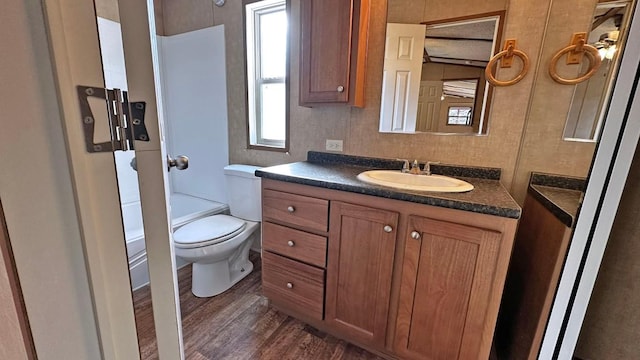 full bathroom with vanity, hardwood / wood-style floors, toilet, and washtub / shower combination