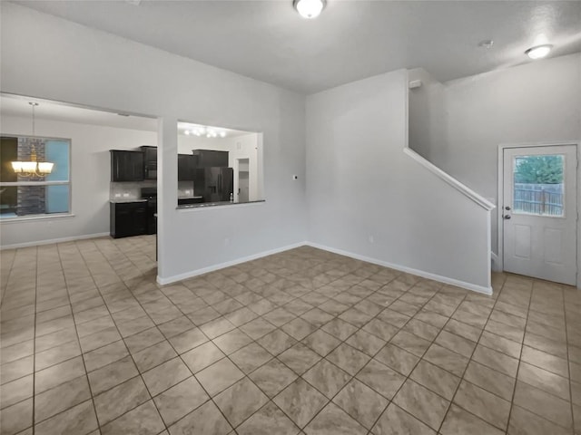 unfurnished living room featuring light tile patterned floors and an inviting chandelier