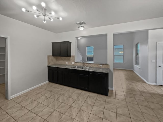 kitchen with light stone countertops, sink, light tile patterned flooring, and black dishwasher