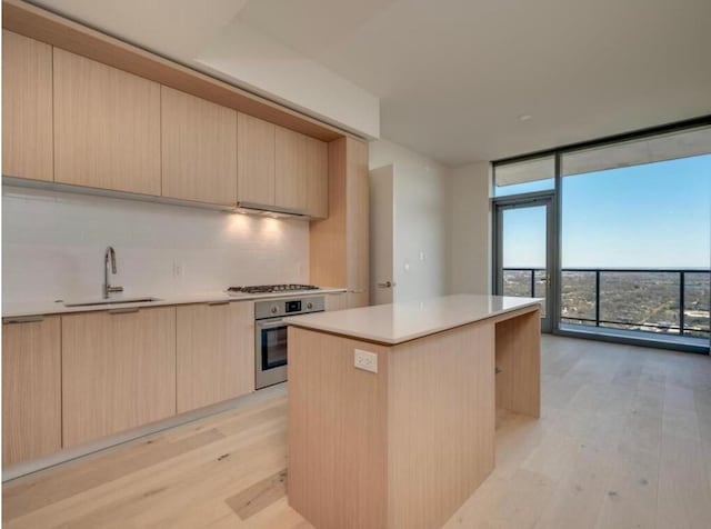 kitchen featuring light brown cabinets, expansive windows, backsplash, a kitchen island, and appliances with stainless steel finishes