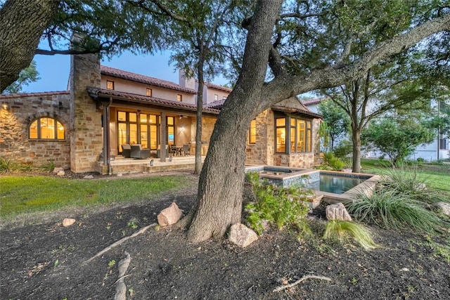 back of property featuring a patio and a pool with hot tub