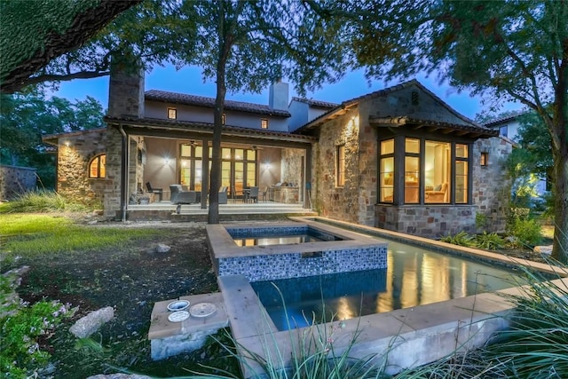 rear view of house with a swimming pool with hot tub and a patio