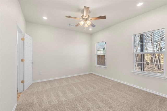 empty room featuring light carpet, a wealth of natural light, and ceiling fan