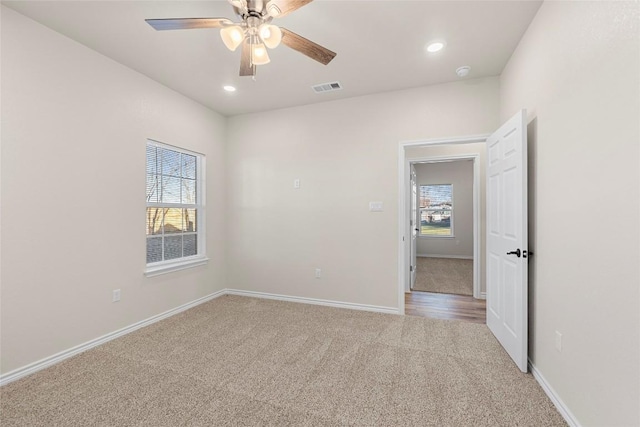 carpeted empty room with ceiling fan and a wealth of natural light