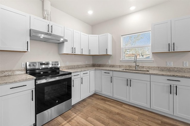 kitchen with white cabinets, sink, stainless steel electric range oven, light hardwood / wood-style floors, and light stone counters