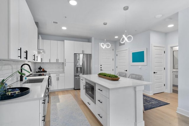 kitchen featuring stainless steel fridge, built in microwave, a center island, white cabinetry, and hanging light fixtures