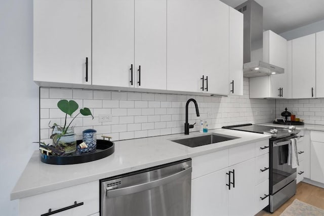 kitchen with white cabinetry, wall chimney range hood, sink, and appliances with stainless steel finishes