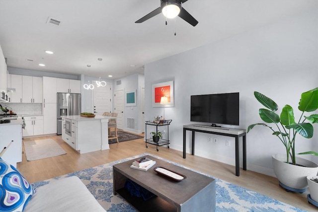 living room featuring ceiling fan, light wood-type flooring, and sink