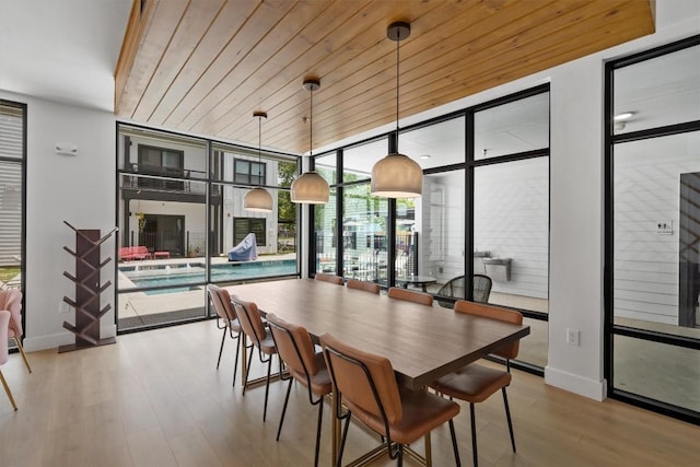 dining area with light hardwood / wood-style floors, a wall of windows, and wooden ceiling