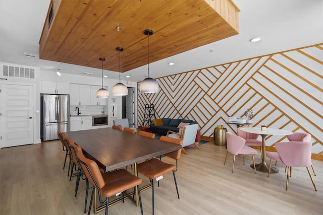 dining space with light wood-type flooring, wood ceiling, and sink