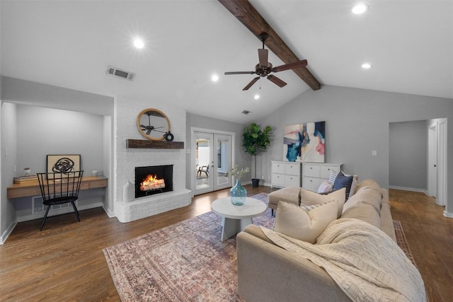 living room featuring french doors, dark hardwood / wood-style flooring, a brick fireplace, ceiling fan, and lofted ceiling with beams