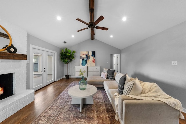 living room featuring french doors, a brick fireplace, ceiling fan, lofted ceiling with beams, and dark hardwood / wood-style floors