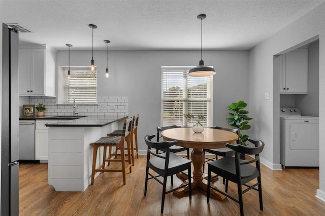 dining space with sink, hardwood / wood-style floors, a textured ceiling, and washer / dryer