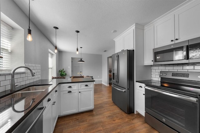 kitchen featuring pendant lighting, decorative backsplash, white cabinetry, and appliances with stainless steel finishes