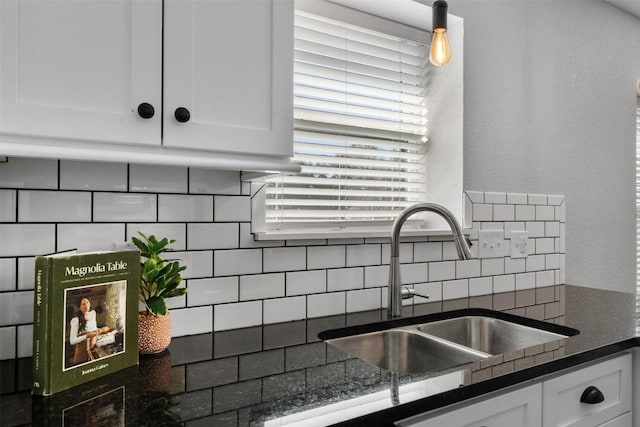 kitchen with tasteful backsplash, white cabinetry, dark stone counters, and sink