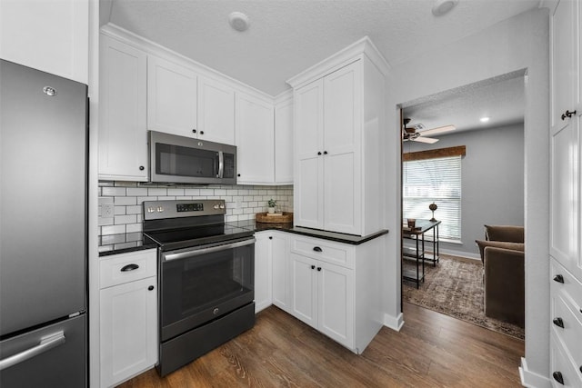 kitchen with appliances with stainless steel finishes, tasteful backsplash, a textured ceiling, dark wood-type flooring, and white cabinetry