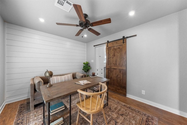 dining room featuring dark hardwood / wood-style floors, a barn door, and ceiling fan