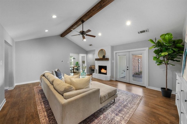 living room with french doors, a brick fireplace, ceiling fan, dark wood-type flooring, and vaulted ceiling with beams