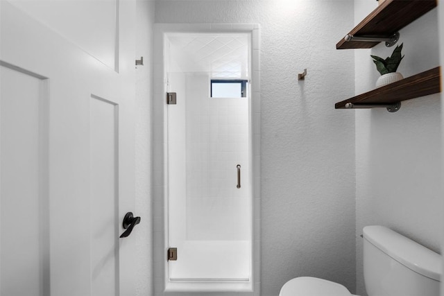 bathroom with a shower with shower door and toilet