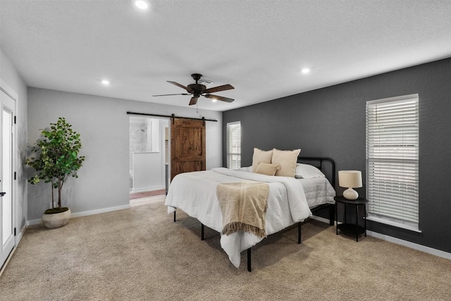 carpeted bedroom with ceiling fan and a barn door